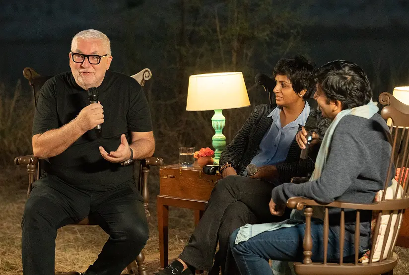 Residents in conversation in a circle of chairs outdoors at night at Dhun