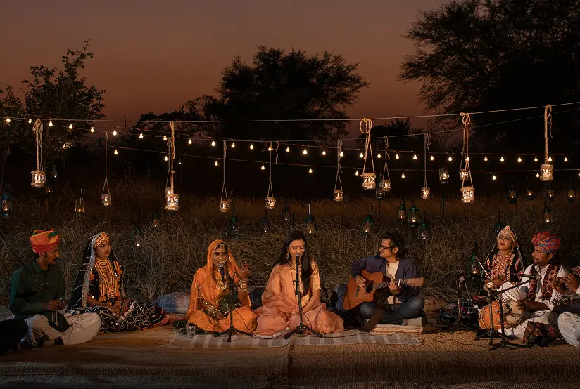 Folk musicians performing under strung lights at Dhun at dusk